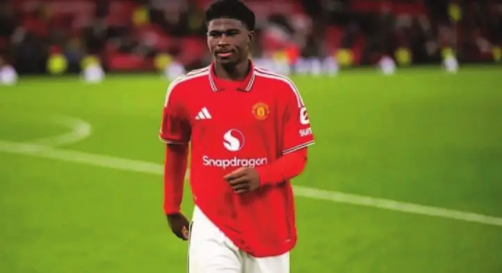 Carlos Baleba sous le maillot rouge de Manchester United, sur la pelouse d’Old Trafford.