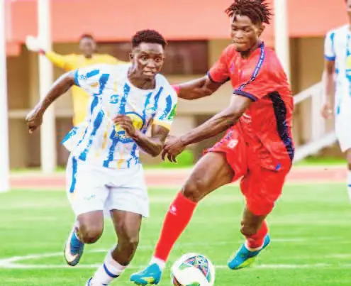 Un joueur de Colombe en maillot rayé bleu et blanc à la lutte avec un joueur de Teungueth FC en rouge.