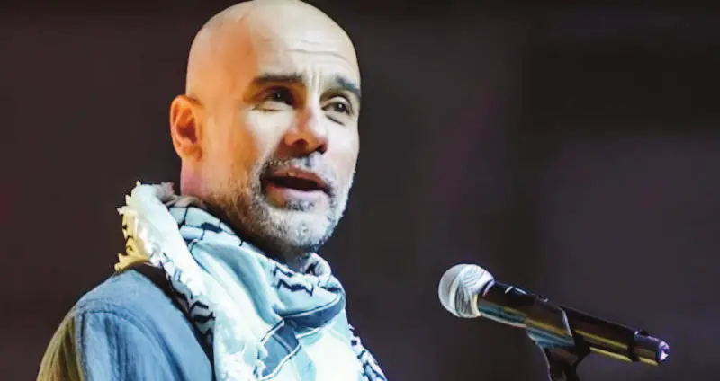 Pep Guardiola s’exprime au micro, un keffieh autour du cou.