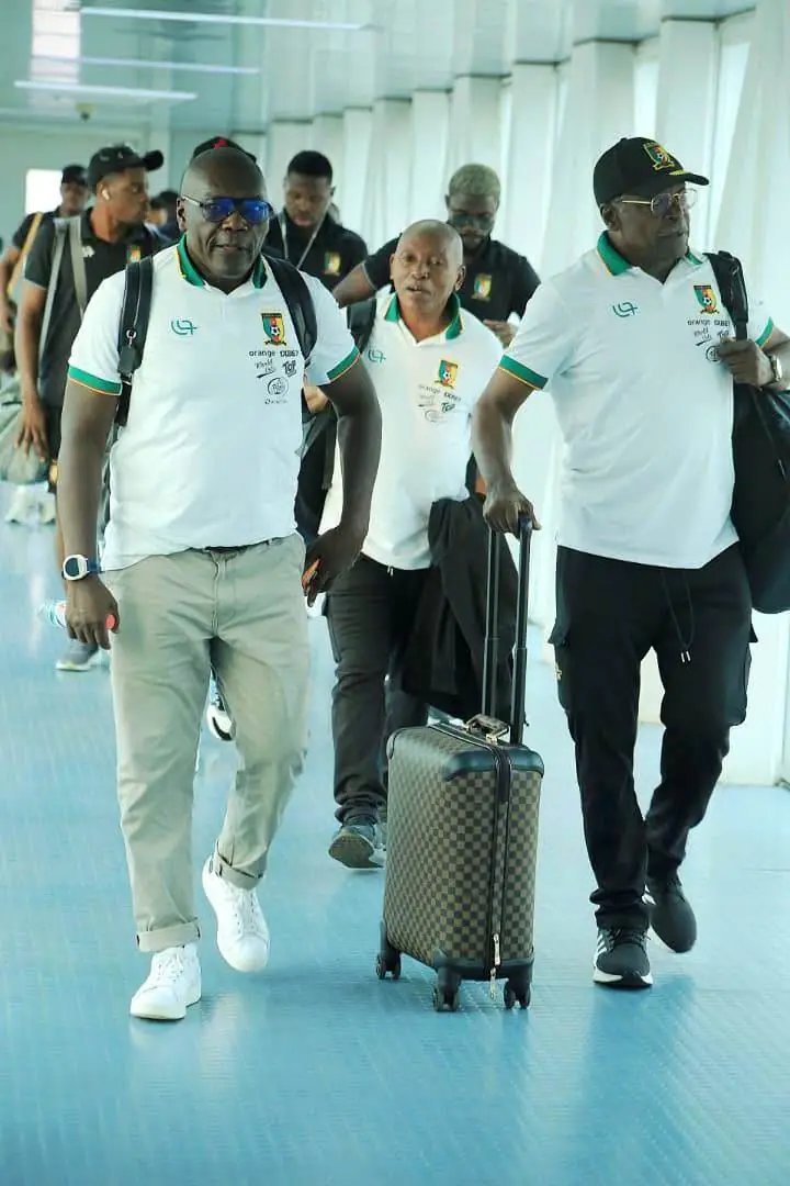 Des membres de la délégation camerounaise traversent un terminal avec leurs bagages.