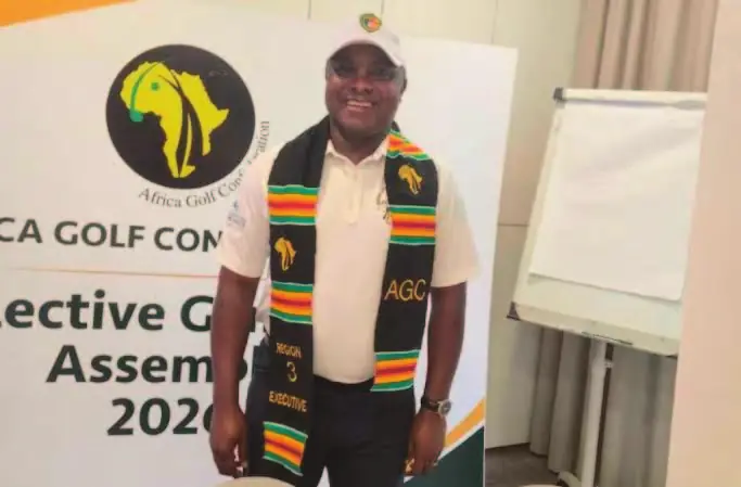 Louis Deschamps Lothin Elessa, en étole aux couleurs africaines, devant le logo de l’Africa Golf Confederation.