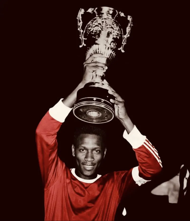 Jean Manga Onguené brandit un trophée sous le maillot rouge du Canon de Yaoundé.