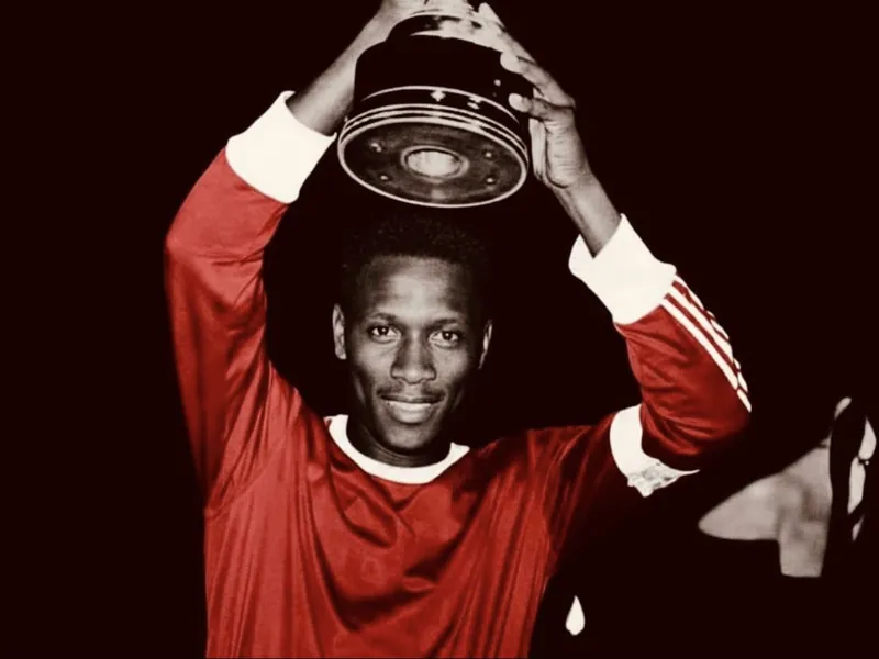 Jean Manga Onguené brandit un trophée sous le maillot rouge du Canon de Yaoundé.