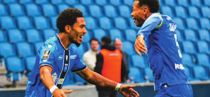 Danny Namaso, maillot bleu de l’AJ Auxerre, célèbre un but avec un coéquipier.