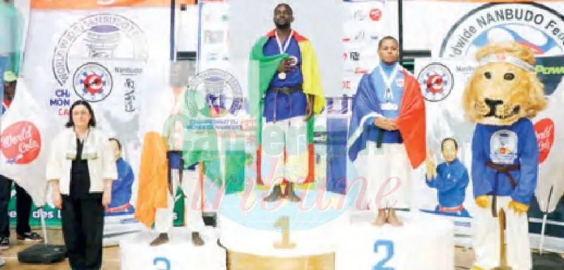 Un nanbudoka camerounais drapé du drapeau national sur la plus haute marche du podium.