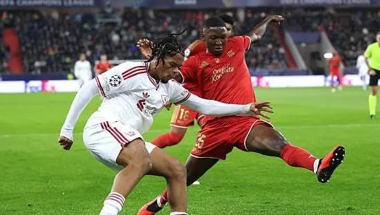 Yvan Dibango, maillot blanc du LASK, à la lutte avec un joueur de Liverpool en Ligue des champions.